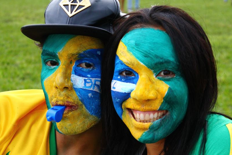 torcedores com rosto pintado com a bandeira do brasil